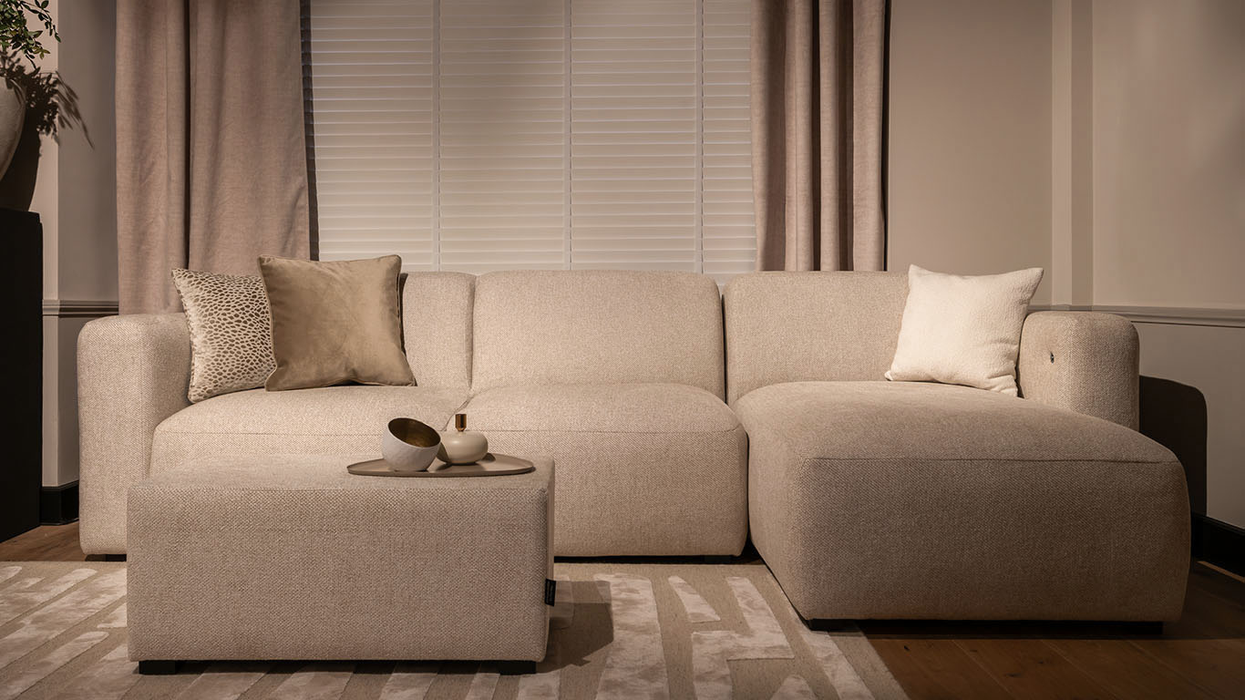 Stijlvolle UrbanSofa Pebble Loungebank in de stof Rio Sand met bijpassende Pebble Comfort Console Hocker.